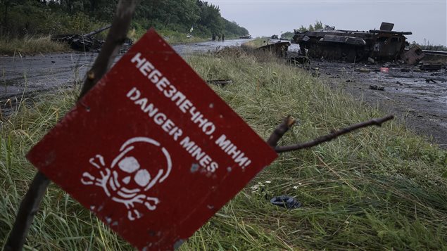 A destroyed military vehicle is seen near a landmine warning sign just outside the eastern Ukrainian town of Slaviansk July 7, 2014. 