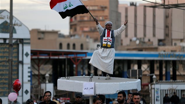 عراقي يرفع علم بلاده في ساحة التحرير في وسط بغداد في العاشر من الشهر الجاري احتفالاً بالنصر النهائي على تنظيم "الدولة الإسلامية" المسلح ("داعش").