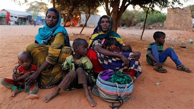 Newly internally displaced women from drought-hit area sit with their children as they wait for help in Dollow. 