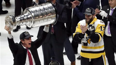 Pittsburgh Penguins head coach Mike Sullivan hoists the Stanley Cup as Bryan Rust (17) watches after defeating the Nashville Predators 2-0 in Game 6 of the NHL hockey Stanley Cup Final in Nashville, Tenn. No Canadian-based team has won the title since the Montreal Canadiens in 1993.