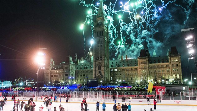 Skaters on the Canada 150 ice rink look on as fireworks explode above Centre Block's Peace Tower during the illumination launch ceremony of Christmas Lights Across Canada on Parliament Hill in Ottawa on Dec. 7, 