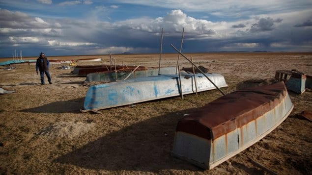 In this Jan. 11, 2016 photo, a fisherman walks along the abandoned boats in the dried up Lake Poopo, on the outskirts of the town of Untavi, Bolivia 