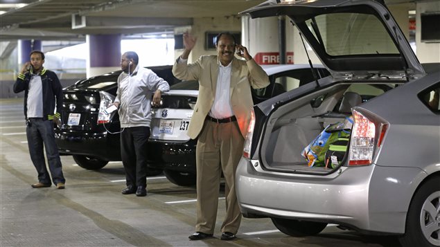 Hassan Farah, right, a driver for Uber Technologies Inc., waves as his customer approaches his vehicle at Seattle-Tacoma International Airport, Thursday, March 31, 2016 in Seattle. 