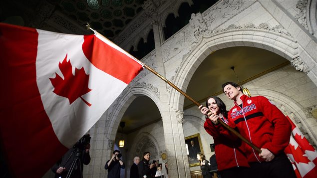 Tessa Virtue and Scott Moir practice waving the flag after the announcement was made on Parliament hill.