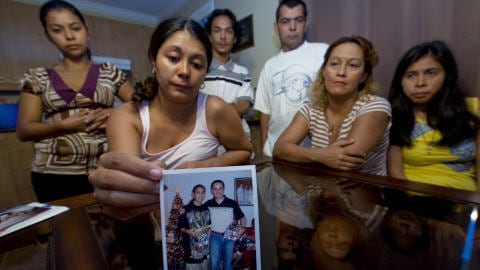 Patricia Villanueva tient une photo de son frère, Freddy, entourée par les membres de la famille.