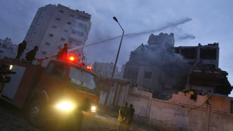 Des pompiers palestiniens arrosaient lundi des bâtiments détruits par l'aviation israélienne.