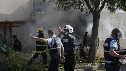 Des policiers et des pompiers israéliens à Sderot, après la chute d'une roquette sur la ville, dimanche.