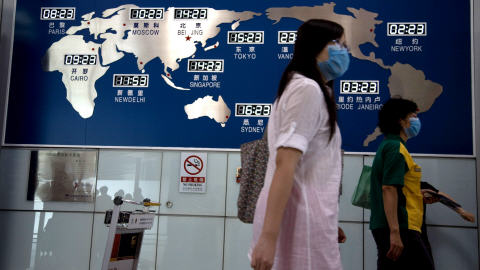 Deux Chinoises passent devant une carte des fuseaux horaires à l'aéroport de Pékin.