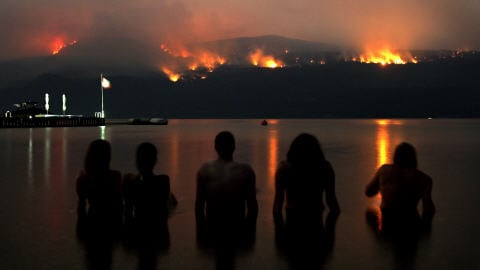 Des amis regardent du lac Okanagan les feux de forêt de Terrace Mountain, au nord de Kelowna