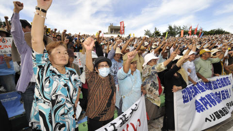 Des manifestants le poing levé au rassemblement qui a eu lieu à Okinawa, dimanche.