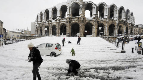 Des passants s'amusent avec la neige près du colisée romain d'Arles, dans le sud-est de la France.