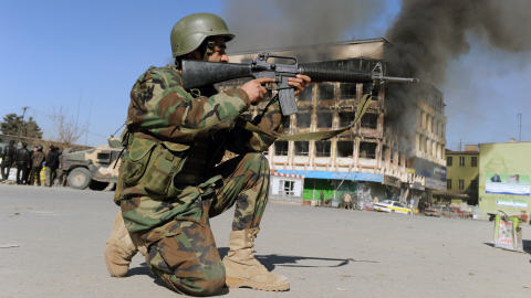 Un soldat prend position devant un centre commercial en feu à Kaboul.