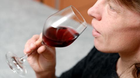 Une femme boit du vin rouge