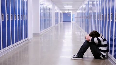 Jeune homme assis dans un couloir d'école