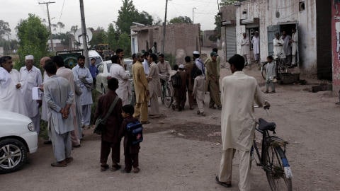 Des résidents de Mohib Banda s'agglutinent devant la résidence cadenassée de la famille Shahzad.