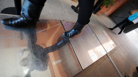 Une femme marche le 13 avril 2010 à Toulouse sur un trottoir électrique qui produit de l'énergie et s'allume grâce au piétinement.
