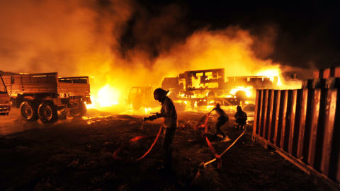 Les pompiers tentent d'éteindre les camions incendiés.