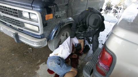 Un policier non identifié retourne le corps d'un homme abattu par la police alors qu'il tentait de fuir l'ouragan Katrina, le 4 septembre 2005.