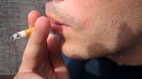 Un adolescent fume une cigarette