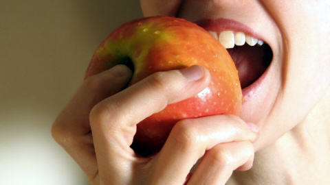 Une femme croque dans une pomme