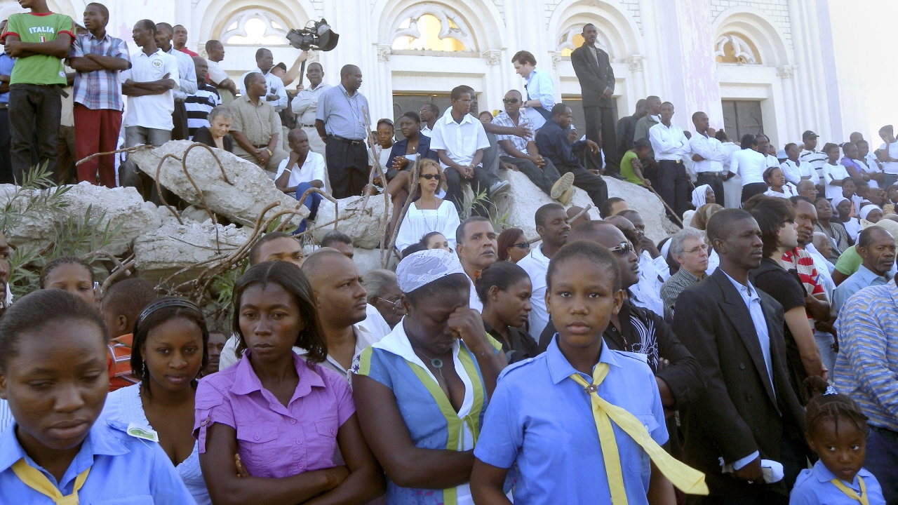 Des Haïtiens prient au pied de la cathédrale Notre-Dame, à Port-au-Prince.