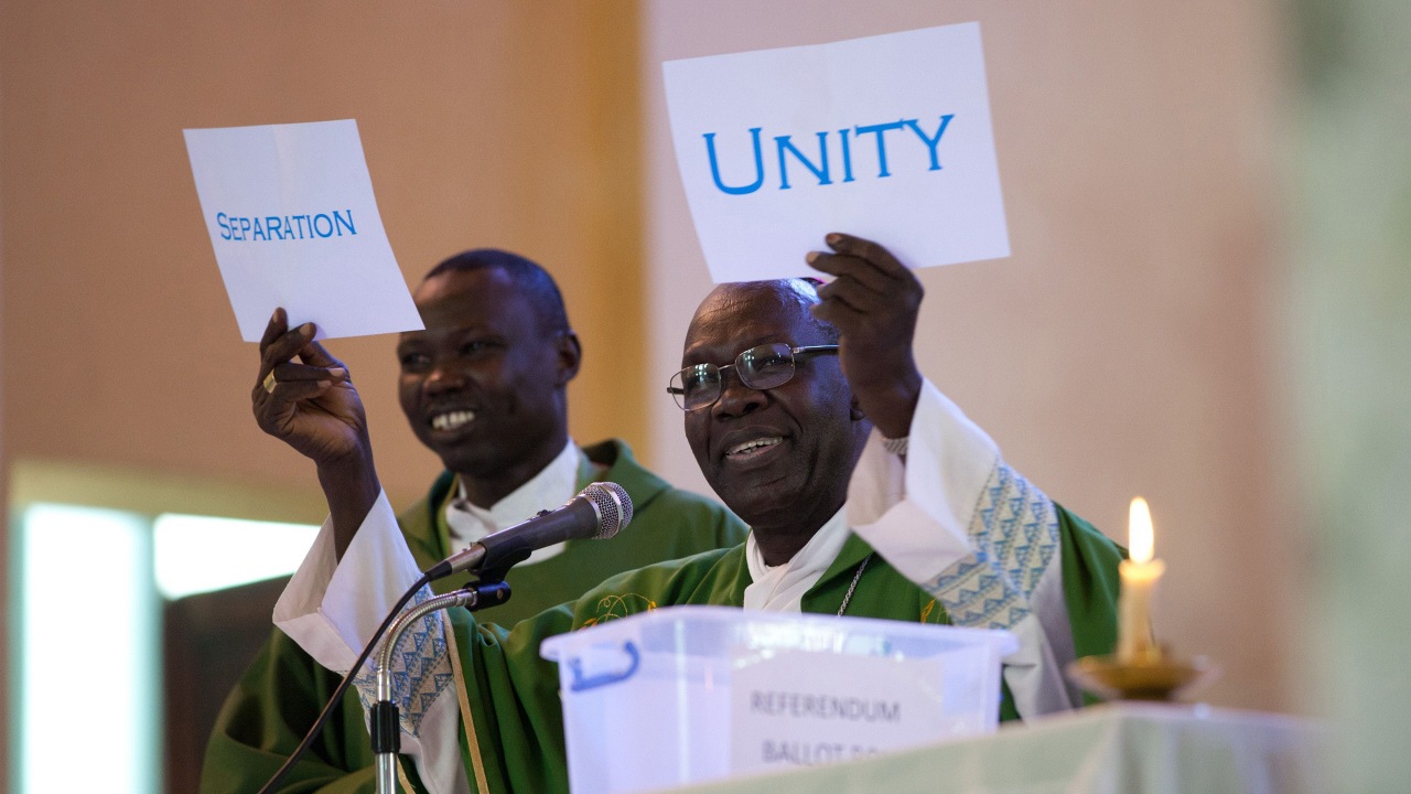 Dans la cathédrale de Juba, un prêtre montre des cartons sur lesquels sont écrits « unité » et « séparation » lors de la messe de dimanche, le 16 janvier, au lendemain du référendum. 