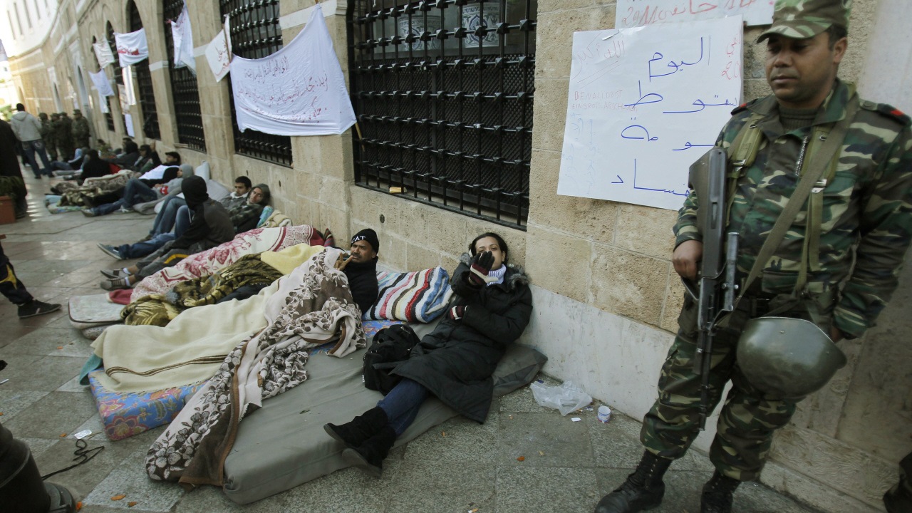 Un soldat tunisien monte la garde devant les bureaux du premier ministre Gannouchi. À ses côtés, des jeunes qui ont passé la nuit à la belle étoile pour venir réclamer la démission du chef du gouvernement de transition.