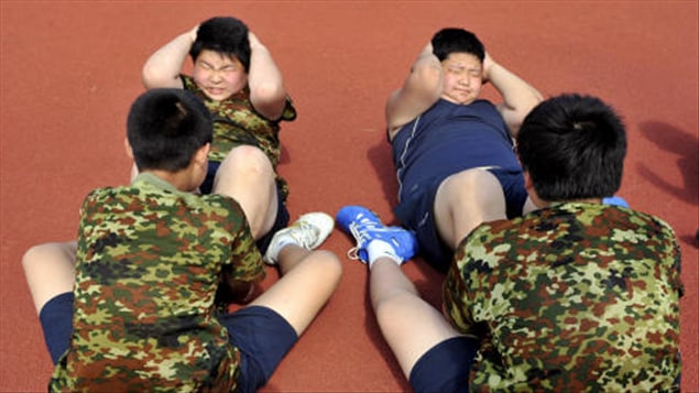 Des enfants obèses chinois peinent à faire des redressements assis.
