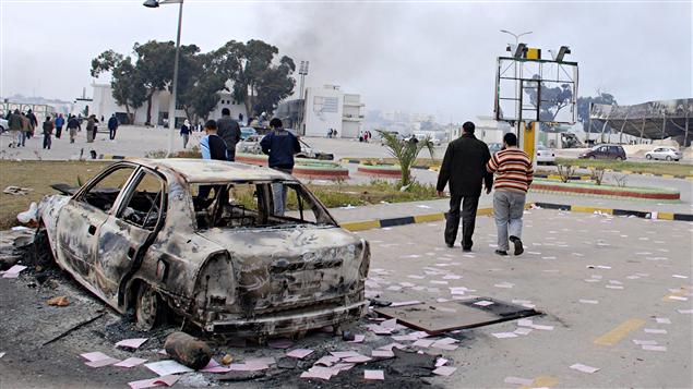 Des Libyens marchent dans les rues dévastées de Benghazi.