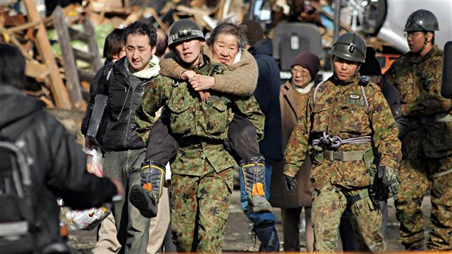 Un soldat japonais porte secours à une femme âgée à Kesennuma, dans le nord-est du Japon.