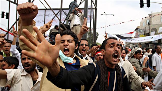 Des hommes manifestent en criant à Sanaa, au Yémen, après que la police ait tué au moins trois manifestants samedi.