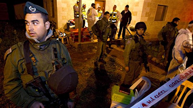 Des policiers et des militaires israéliens sont aux abords d'une maison où une famille de colons a été assassinée au couteau.