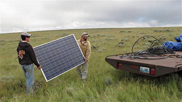 Des hommes s'apprêtent à instaler des panneaux solaires sur une ferme.