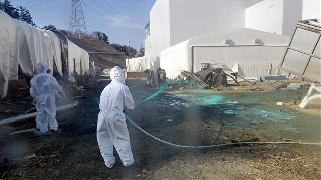 Des employés de Tepco pulvérisent de la résine sur le sol à proximité des bâtiments des réacteurs pour éviter la propagation de substances radioactives.