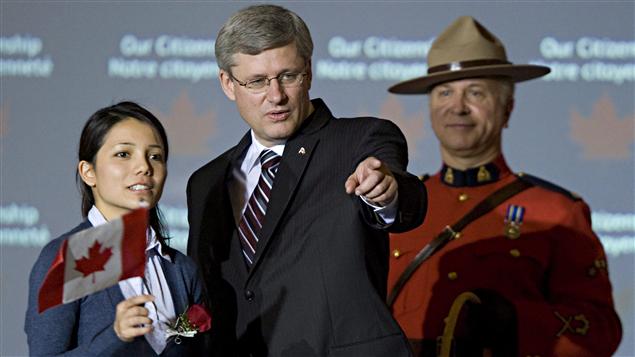 Au cours d'une cérémonie tenue en octobre 2010, Stephen Harper se tient à côté d'une jeune femme qui a reçu sa résidence permanente.