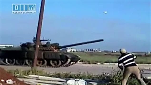 Un homme lance une pierre sur un tank de l'armée syrienne dans la ville de Deraa.