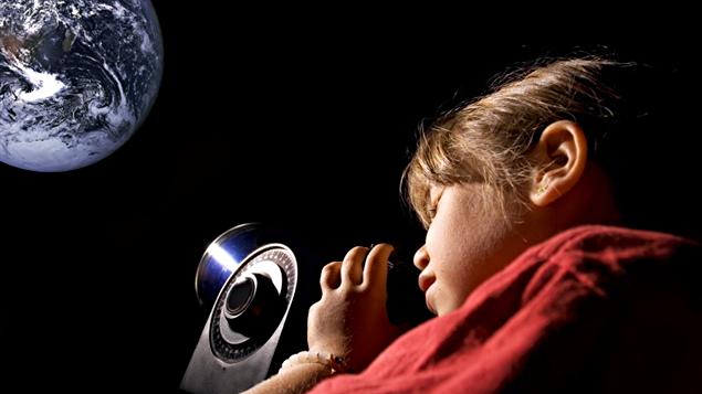 Une jeune fille observe la Lune à l'aide d'un télescope