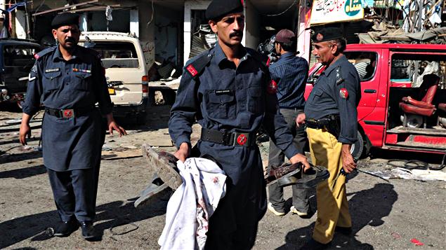 Des agents de sécurité pakistanais collectent les effets personnels des victimes de l’attaque de vendredi commis devant un centre d'entraînement de la police des frontières à Shaqbadar, dans le nord-ouest du Pakistan.