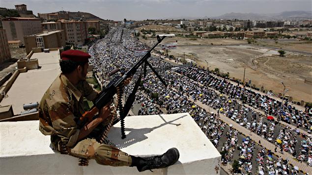 Un soldat fidèle au général Ali Mohsen, rallié à l'opposition, surveille les manifestants qui défilent dans les rues de Sanaa, vendredi.