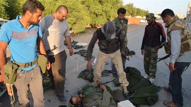 Des rebelles libyens regardent le corp d'un soldat fidèle à Mouammar Kadhafi dans le village d’al-Rayayna