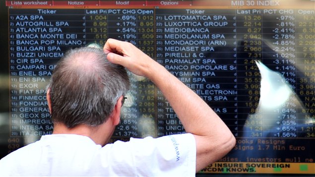 Un homme regarde les cotes à la Bourse de Milan lundi.
