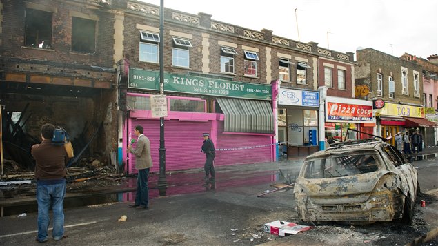 Un policier installe un cordon de sécurité devant un commerce incendié à Tottenham