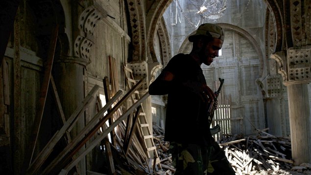 Un rebelle libyen marche dans les décombres d'une mosquée, à Sabrata, qui a servi d'abri durant les bombardements du régime de Mouammar Kadhafi.