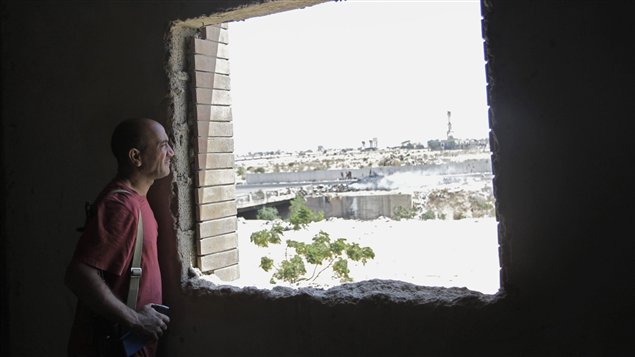 Un rebelle libyen observe les combats qui se déroulent près du complexe de Bab Al-Aziziya.