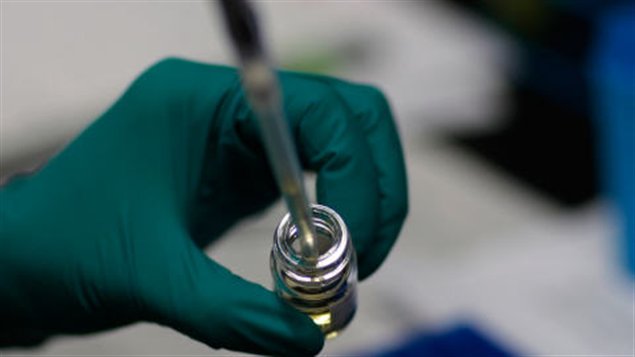 Un technicien de laboratoire extrait du liquide d'une fiole.