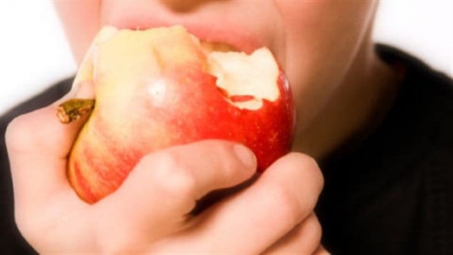 Un garçon croque dans une pomme.