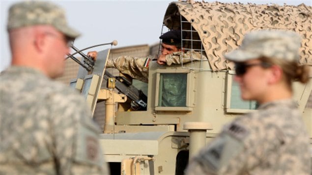 Deux soldats américains discutent devant un véhicule de police militaire irakien le 29 juillet 2010 à Bagdad.