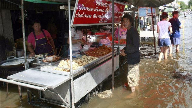 Thailandais achetant de la nourriture, les pieds dans l'eau.