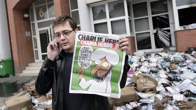 Le directeur de la publication de Charlie Hebdo montre le numéro spécial sur le printemps arabe devant les locaux incendiés de l’hebdomadaire.