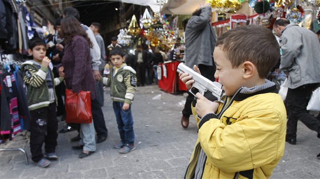 Un enfant joue avec un fusil jouet, samedi, dans à Damas.